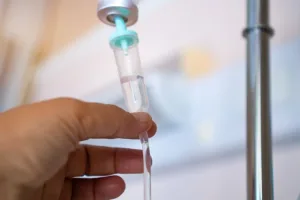 Evde serum uygulaması için damar yolu açmaya hazırlanan sağlık personeli ve steril serum seti.