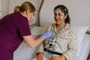 Evde muayenede doktorun hastayı dinlemesi, tansiyon ölçmesi ve kısa notlar alması.