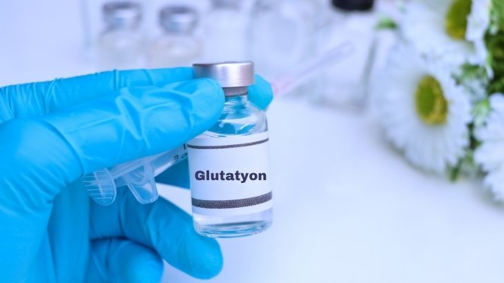 Glutatyon serumu uygulanırken sağlık personelinin serum setini kontrol ettiği, hastanın kolunda damar yolu bulunan bir sahne.