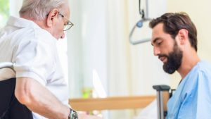 Evde doktorun yaşlı hastanın nabız ve tansiyonunu ölçmesi, yanında ilaç kutularının durması.