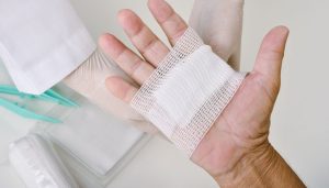 Evde yaşlı bireye profesyonel pansuman ve sıvı tedavisi uygulayan hemşireyi gösteren bir görsel.