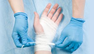 Evde hastanın yarasına profesyonel şekilde bakım yapan hemşireyi gösteren bir görsel.