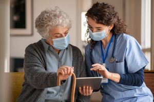 Evindeki rahat ortamında tedavisi süren hastanın sağlık verilerini inceleyen uzman doktor ve ona eşlik eden evde bakım sağlık ekibi.